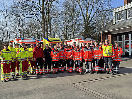 Gruppenbild Eine Gruppe von Einsatzkräften in Einsatzkleidung vor drei Rettungswägen.