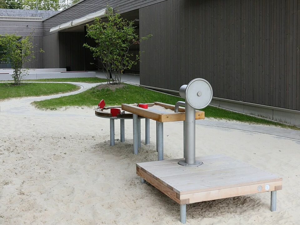 Sandkasten Ein Sandkasten in einem Innenhof eines modernen Gebäudes mit einem Wasserspielzeug.