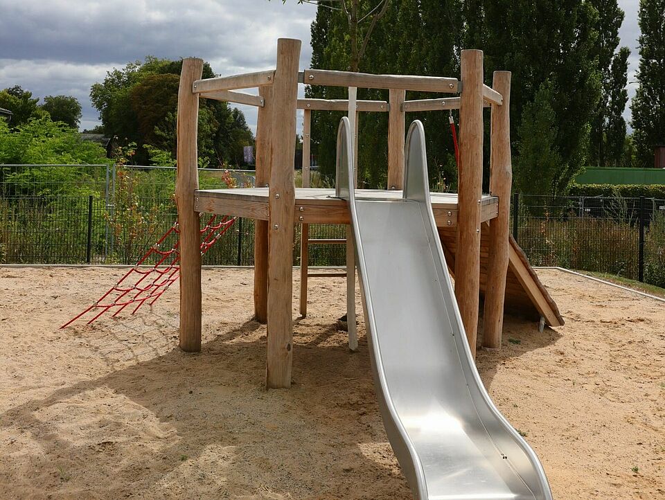 Klettergerüst Ein Klettergerüst mit einer Rutsche in einem Sandkasten